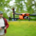 A man flies a drone in a backyard