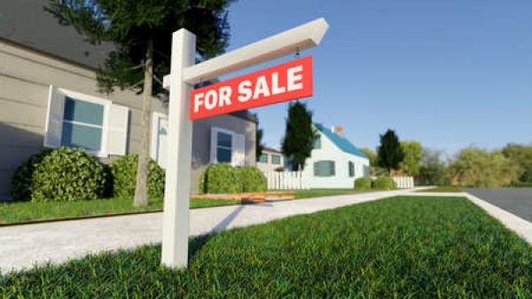 A for sale sign sits in front of a house