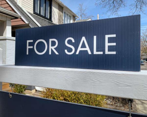 A for sale sign sits in front of a home