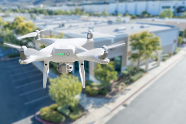 Unmanned Aircraft System Quadcopter Drone In The Air Near Corporate Industrial Building.